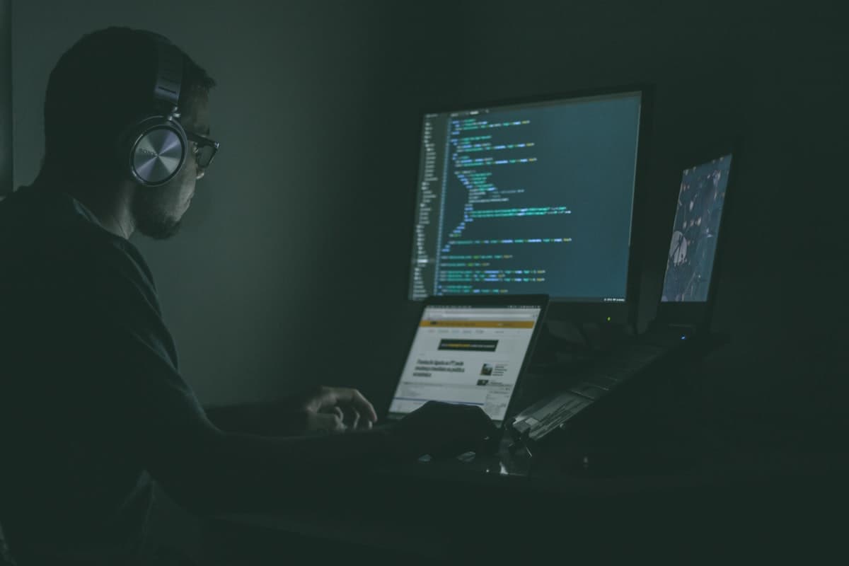 Developer at a dark-themed workstation with code on screens